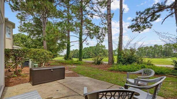 An outdoor patio with a table and chairs, surrounded by trees and a lawn. - Myrtle Golf Escape At Legends-pool-pet Friendly (Myrtle Beach)