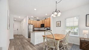 A modern kitchen with wooden cabinets, a central island, and a dining area with a wooden table and chairs. - Myrtle Golf Escape At Legends-pool-pet Friendly (Myrtle Beach)