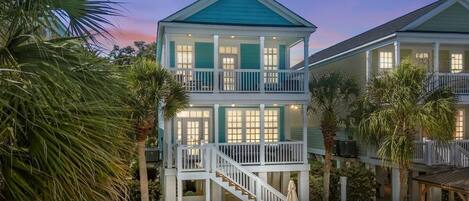 A two-story house with a balcony, a staircase, and a patio area with outdoor furniture.
