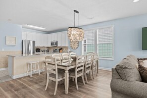 A modern kitchen with white cabinets, a central island, and a chandelier. - Barefoot Beach-steps To Beach, Pool, Pet Friendly (Surfside Beach)