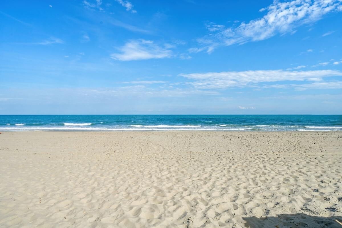 A wide sandy beach with gentle waves and a clear blue sky.