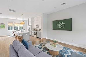 A modern living room with a grey sofa, a coffee table, and a dining area with a white table and chairs. - Sincerely Shem II- 7 min to Beach and Dtwn CHS (Mount Pleasant)