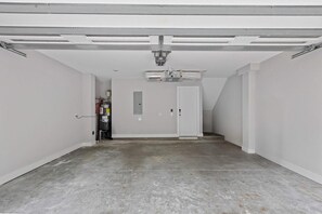 A clean, empty garage with a concrete floor, a door, and a ceiling fan. - Sincerely Shem II- 7 min to Beach and Dtwn CHS (Mount Pleasant)