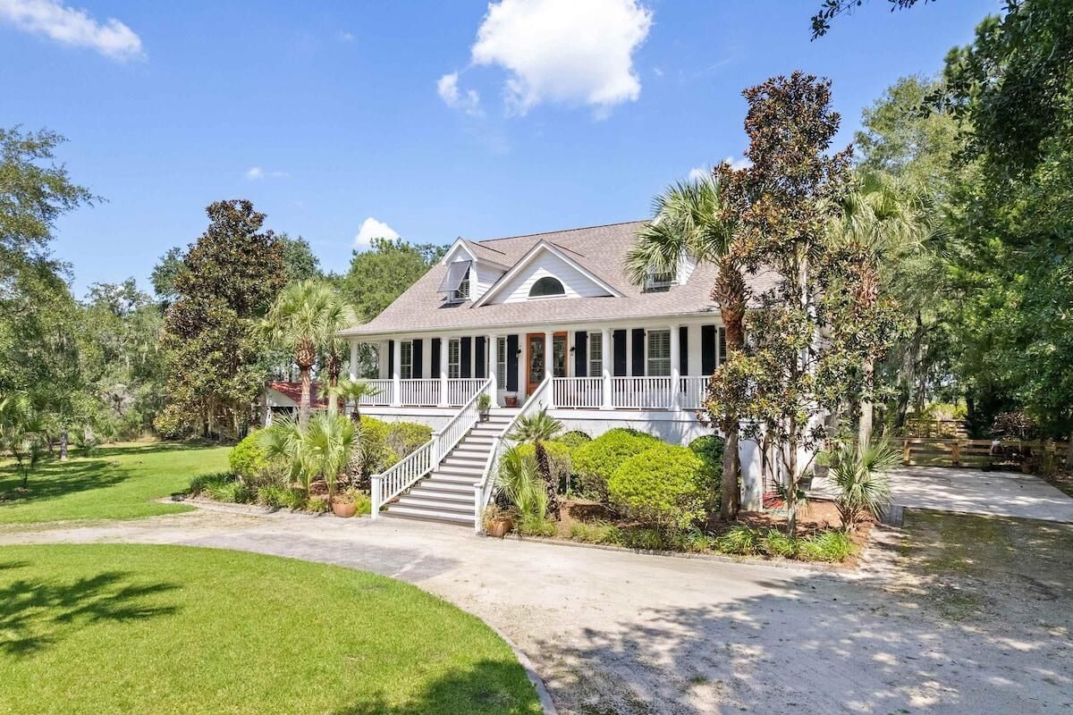 A large, single-story house with a covered porch, a central staircase, and a well-maintained lawn.