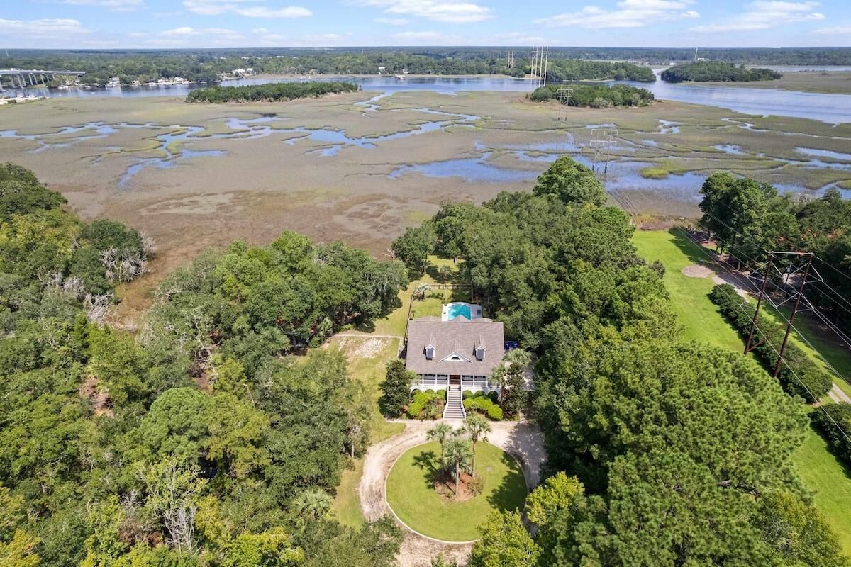 An aerial view of a house surrounded by dense forest and wetlands.