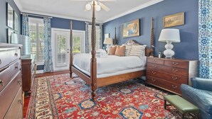 A bedroom with a four-poster bed, a ceiling fan, a large window with shutters, a patterned rug, and a dresser. - Boview Hall- Pool, Hot Tub-15 Mins to Kiawah (Johns Island)