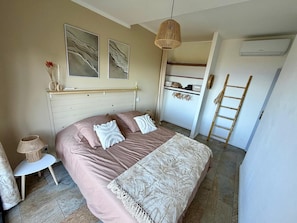 A bedroom with a bed, a bedside table, a lamp, a wardrobe, and a hanging light fixture. - "Kaz mer veille" Villa  (Les Avirons)