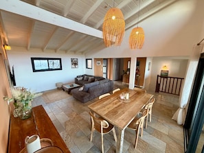 A spacious living area with a wooden dining table, a sofa, and a TV. - "Kaz mer veille" Villa  (Les Avirons)