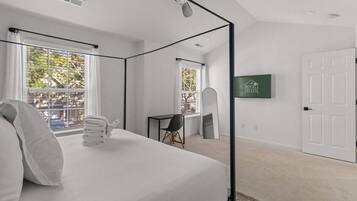Ein modernes Hotelzimmer mit einem großen Bett, einem Schreibtisch und einem Fernseher.