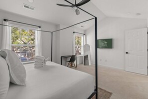 A modern hotel room with a large bed, a desk, and a television. - Boho Ferry- Mins From Credit One- Pet Friendly (Charleston)