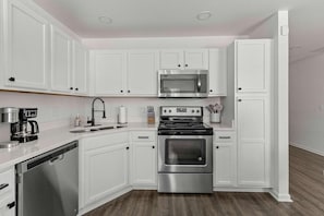 A modern kitchen with white cabinetry, stainless steel appliances, and a dishwasher. - Boho Ferry- Mins From Credit One- Pet Friendly (Charleston)