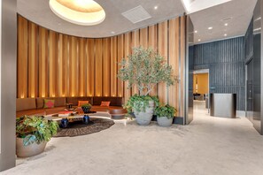 A modern lobby with a curved ceiling, a seating area with sofas and a coffee table, and a large potted tree. - E11EVEN Studio · Bay Views + Rooftop Day Club Pool (Miami)