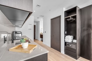 A modern kitchen with a built-in oven, a stainless steel range hood, and a wooden tray with a potted plant. - E11EVEN Studio · Bay Views + Rooftop Day Club Pool (Miami)