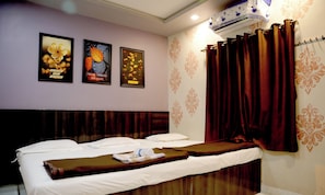 A hotel room with a bed, a wall-mounted air conditioner, and three motivational posters.