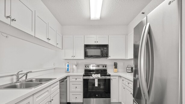 A modern kitchen with white cabinets, stainless steel appliances, and a wooden floor. - Beachfront Breeze @ Sea Castle North Myrtle Beach (North Myrtle Beach)
