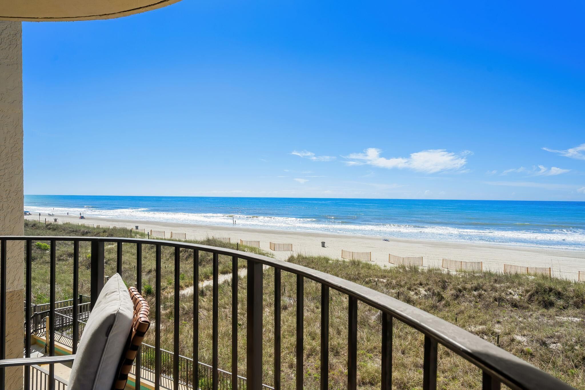 A balcony with a view of a beach and ocean.
