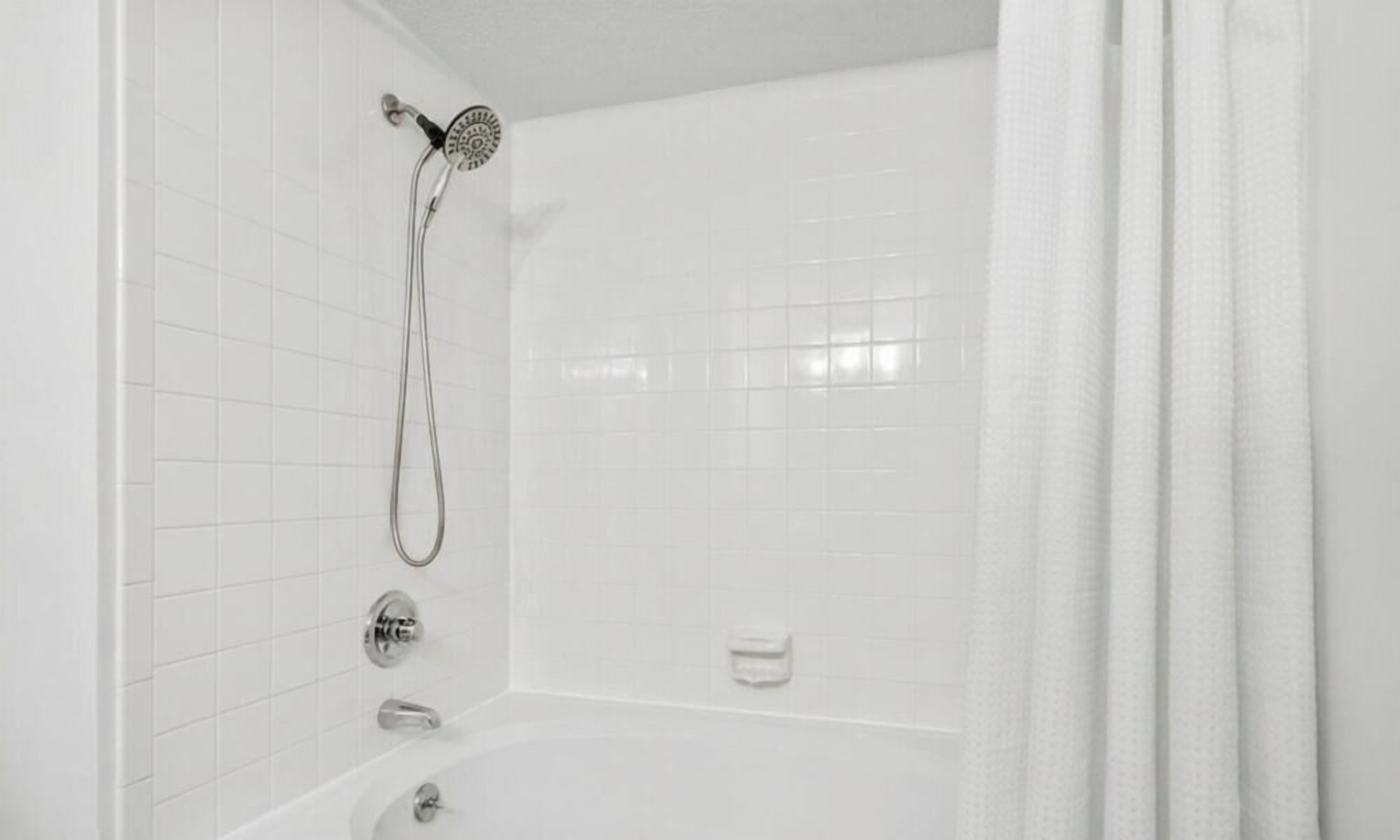 Een badkamer met een douche, bad en toilet.