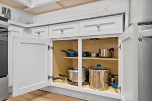 Una cocina con armarios blancos, encimera de madera y diversos utensilios de cocina.