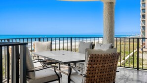 A balcony with a table and chairs, a view of the beach, and a building in the background. - Beachfront Breeze @ Sea Castle North Myrtle Beach (North Myrtle Beach)