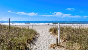 A sandy beach path leading to the ocean with a clear sky. - Beachfront Breeze @ Sea Castle North Myrtle Beach (North Myrtle Beach)