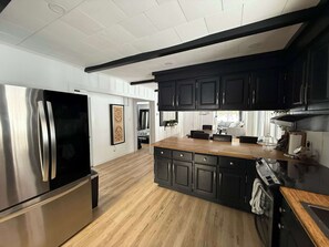 A modern kitchen with stainless steel appliances, dark cabinetry, and a wooden island.