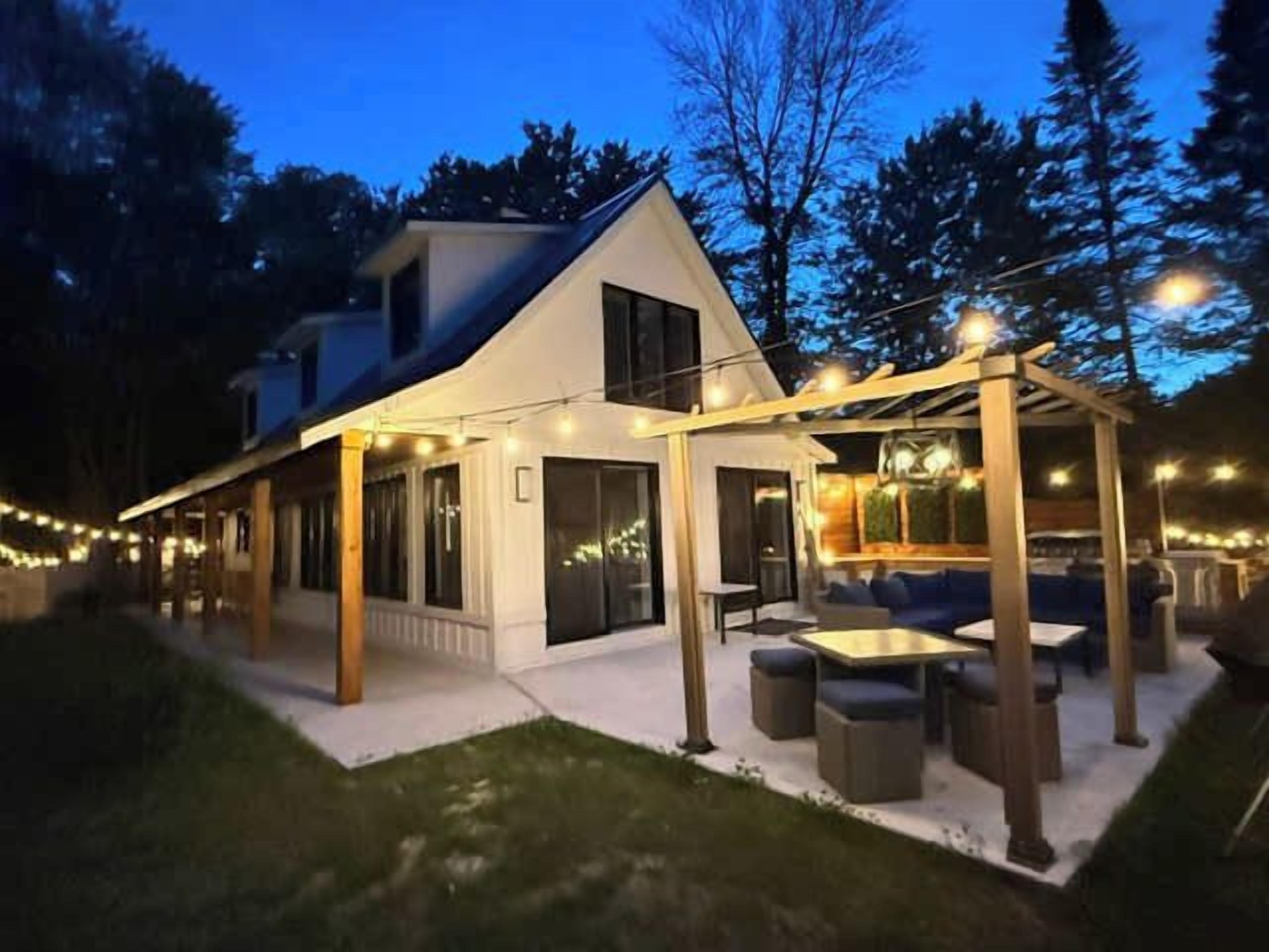 A modern house with a covered outdoor seating area, a patio, and string lights.