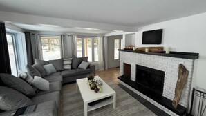 A modern living room with a fireplace, a sofa set, and a coffee table. - Waterfront Relaxation & Adventure | Albert (Pointe-Fortune)
