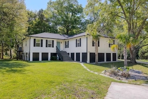 A two-story house with a front porch, a staircase leading to the entrance, and a well-maintained lawn. - The Endless Summer-hot Tub-7 Beds (North Charleston)