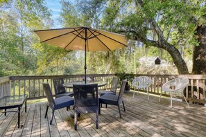 A wooden deck with outdoor furniture, including a table and chairs, and a large umbrella. - The Endless Summer-hot Tub-7 Beds (North Charleston)