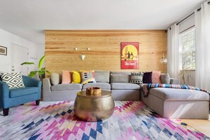 Ein Wohnzimmer mit einer Holzwand, einer Sofagarnitur, einem Couchtisch und einem Poster.