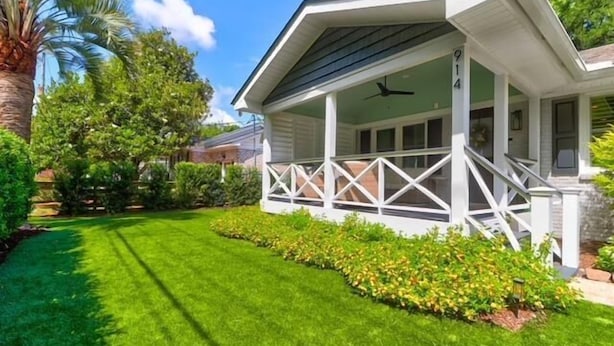 A house with a covered porch, a well-maintained lawn, and a variety of trees and shrubs. - Old Village Palmetto- Pet Friendly (Mount Pleasant)