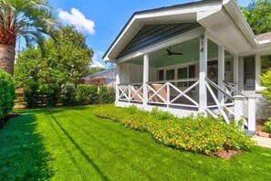 A house with a covered porch, a well-maintained lawn, and a variety of trees and shrubs. - Old Village Palmetto- Pet Friendly (Mount Pleasant)