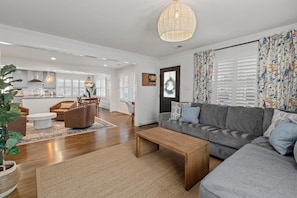A modern living room with a grey sofa, wooden coffee table, and a large potted plant. - Old Village Palmetto- Pet Friendly (Mount Pleasant)
