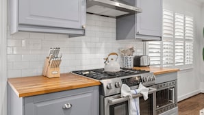 A kitchen with grey cabinets, a stainless steel stove, and a wooden countertop. - Old Village Palmetto- Pet Friendly (Mount Pleasant)