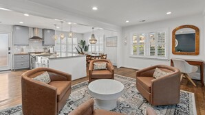 A spacious living area with a central round coffee table, two brown sofas, and a dining area with a wooden table and chairs. - Old Village Palmetto- Pet Friendly (Mount Pleasant)