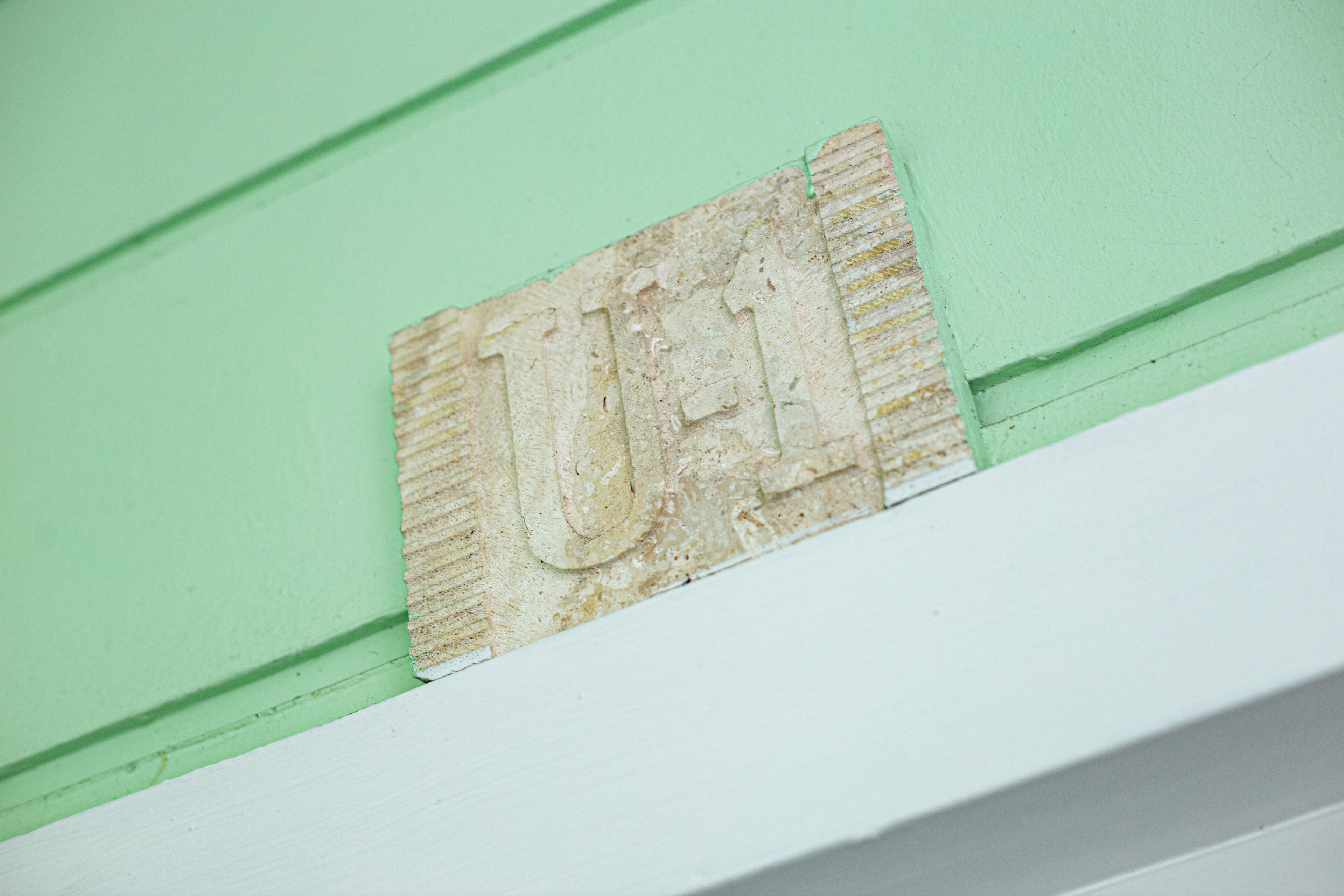 Ein Detailaufnahme einer Wand mit grüner Farbe und weißer Umrandung.