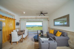 Un espacio de estar con mesa de comedor, sillas, sofá y vista al océano.