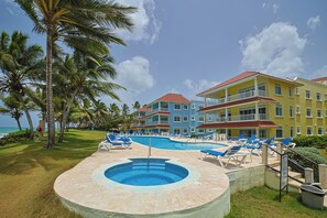 Ein Hotel mit Swimmingpool, Liegestühlen und Palmen.