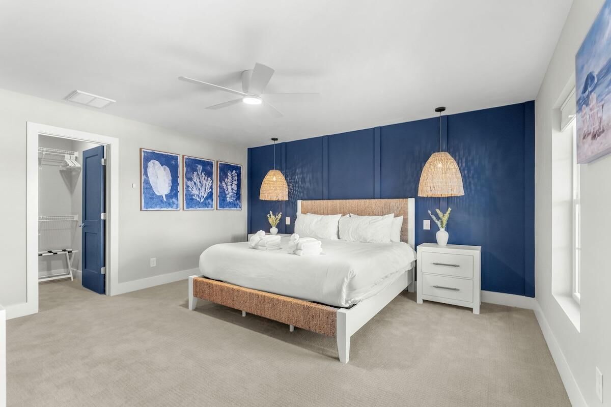 A bedroom with a bed, bedside tables, a ceiling fan, and artwork on the walls.