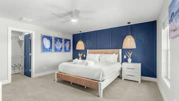 A bedroom with a bed, bedside tables, a ceiling fan, and artwork on the walls.