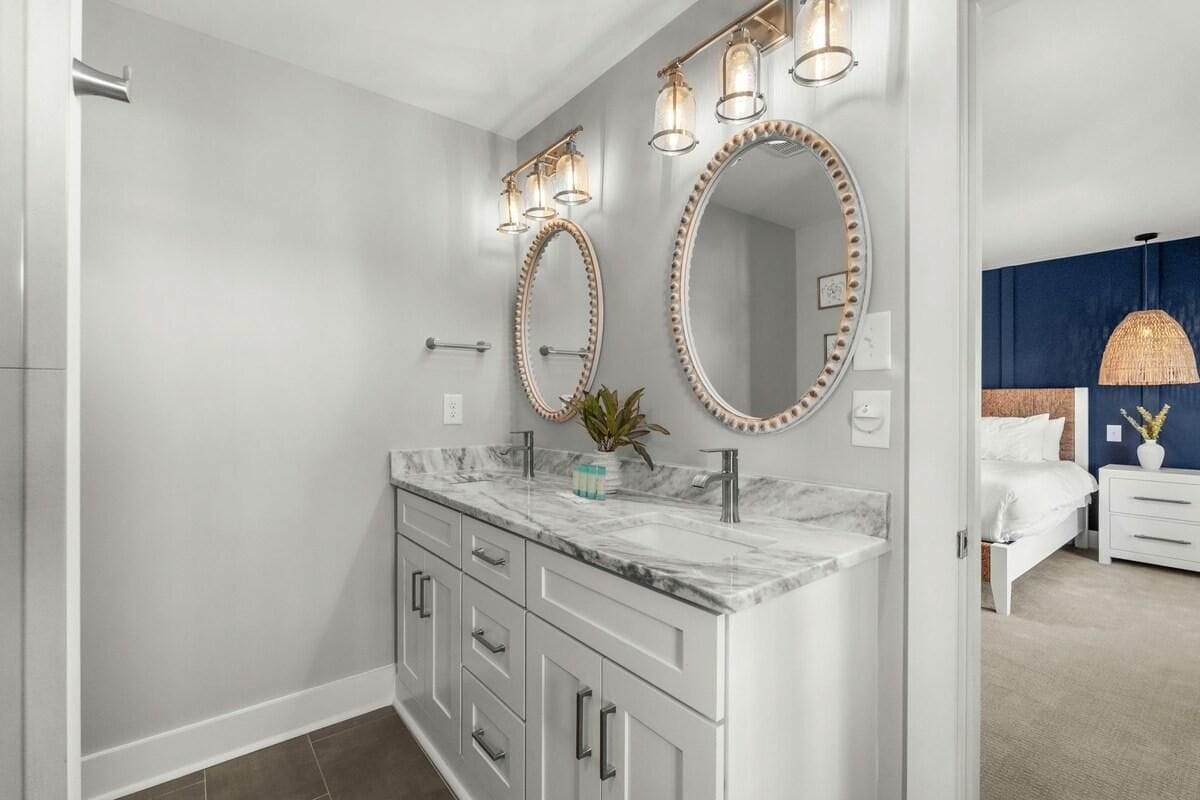 A modern bathroom with a marble vanity, two large mirrors with decorative frames, and a shower area.