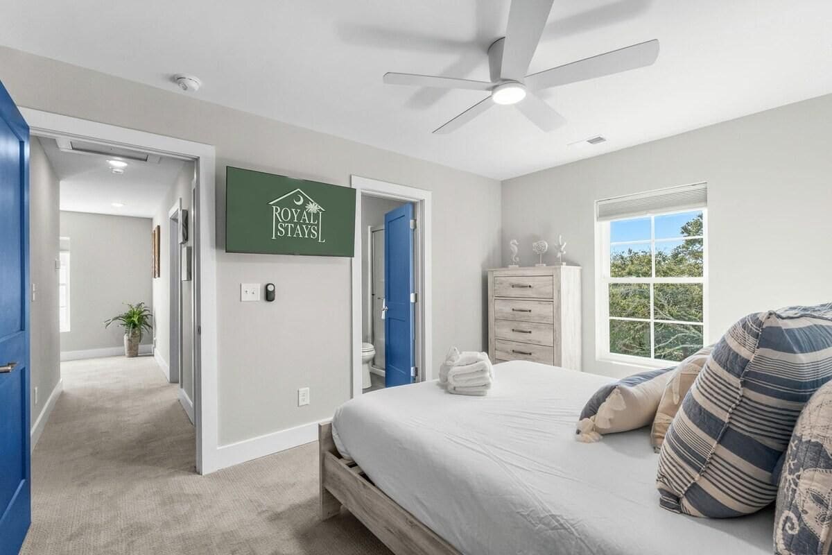 A bedroom with a bed, a ceiling fan, a window, and a sign on the wall.