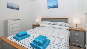 Una camera da letto con un letto, due comodini, una cassettiera e due quadri appesi al muro.