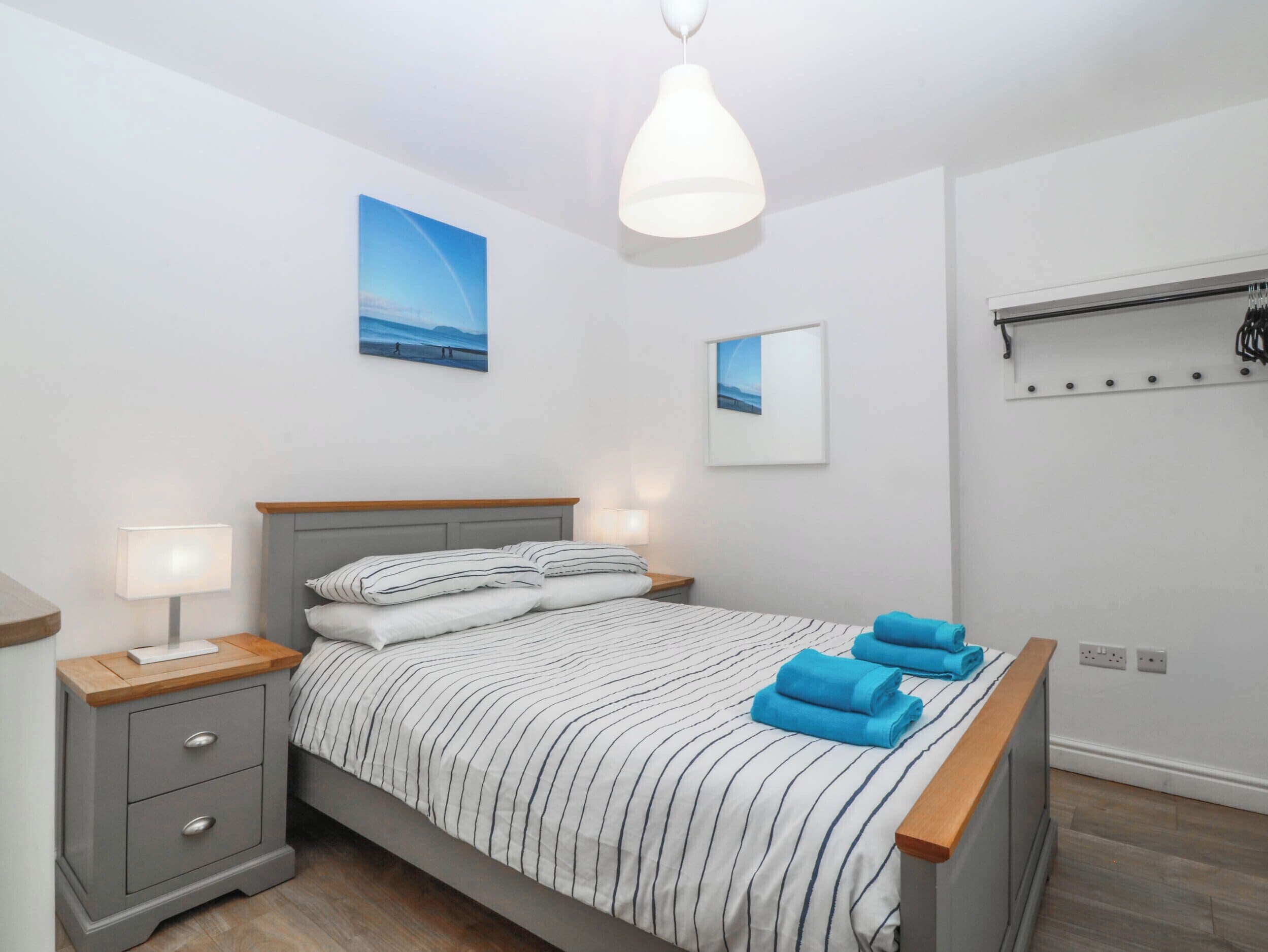 Ein ordentlich eingerichtetes Schlafzimmer mit Bett, Nachttischen und einer Pendelleuchte.