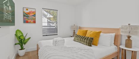 Une chambre moderne avec un lit, un ventilateur de plafond, une fenêtre et une plante en pot.