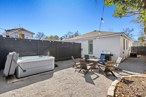 Un jardin avec un jacuzzi, un coin salon extérieur et un barbecue.
