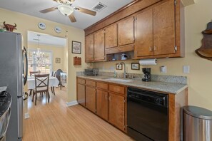 A kitchen with wooden cabinets, a dishwasher, and a granite countertop. - The Victorian Jewel Pet Friendly (Mount Pleasant)