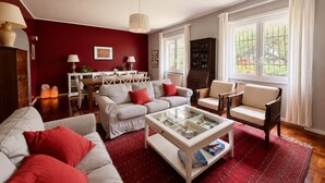 A living room with a red wall, a glass coffee table, and a dining area with a white table and chairs.