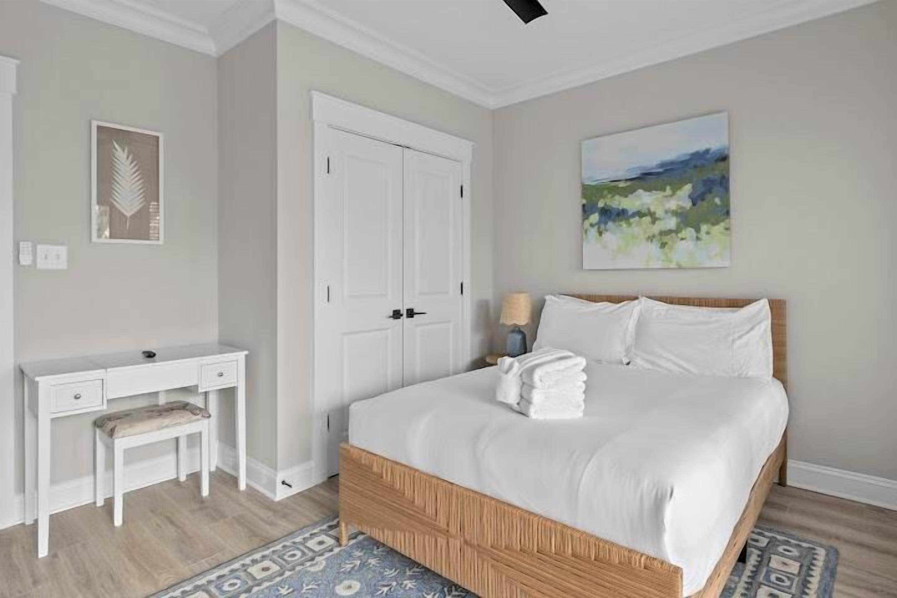 Ein Schlafzimmer mit Bett, Nachttisch, Sessel und einem Bild an der Wand.