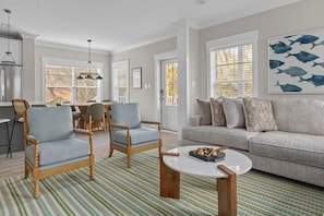 Een woonkamer met een bank, twee fauteuils, een eettafel met stoelen en een salontafel.